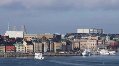 Stockholm, İsveç yolcu feribotu arka planda bir şehir rıhtımı olan sakin bir limandan geçiyor.