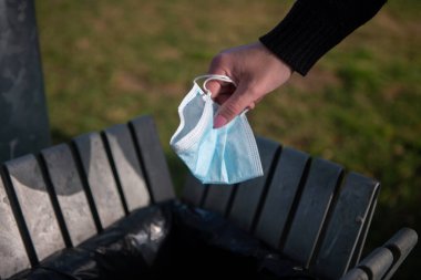 19. ve Coronavirüs 'ün yayılmasını önlemek için cerrahi maske takan bir kadının koluna yakın çekim..