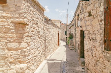 Eski bir köy olan Kıbrıs 'taki Omodos' un güneşli dar caddesi. Güneşli bir günde taş duvarlar ve canlı yeşil bitkiler.