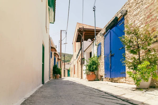 Zonnige smalle straat in het oude dorp Omodos op Cyprus. Stenen muren en levendige groene planten op een zonnige dag. — Stockfoto