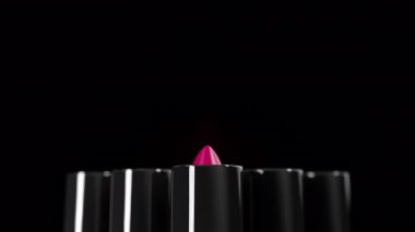 Siyah borulardan çıkan renkli ruj setine yakın plan. Ön manzara ruj izi, sığ bir animasyon ile çıkıyor. Moda, kozmetik, makyaj 3D.