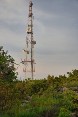 Bu eşsiz fotoğraf Tayland 'da güneşin batışında bir dağın tepesinde duran bir vericiyi ve telefon direğini gösteriyor.