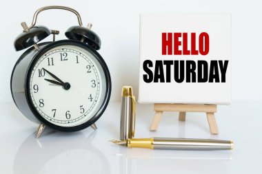 İş ve finans kavramı. Masanın üzerinde bir saat, bir kalem ve üzerinde metin yazan bir stand var - Merhaba Cumartesi