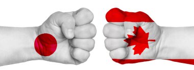 İnsanların mücadelesi kavramı. İki el birbirine kenetlenir ve birbirlerinin karşısındadır. Ülkelerin bayraklarının renklerine boyanmış eller. Kanada Japonya 'ya karşı