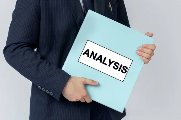 Business concept. A businessman holds a folder with documents, the text on the folder is - ANALYSIS