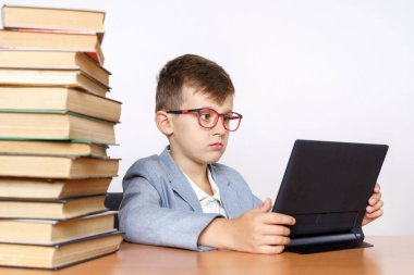 Eğitim konsepti. Öğrenci bir tablet kullanarak ev ödevi yapar. Her iki tarafta da kitapları var..