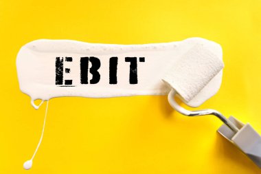 İş ve finans kavramı. Sarı arka planda, yüzey bir fırçayla beyaza boyanır ve üzerine EBIT yazılır.