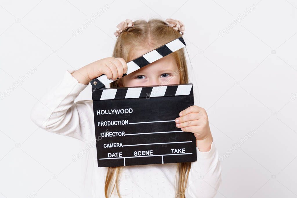Children concept. A girl looks through a clapperboard into the camera. Isolated over white background.