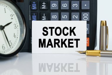 İş ve finans kavramı. Masanın üzerinde bir saat, bir kalem, bir hesap makinesi ve üzerine metin yazılmış bir kartvizit var.