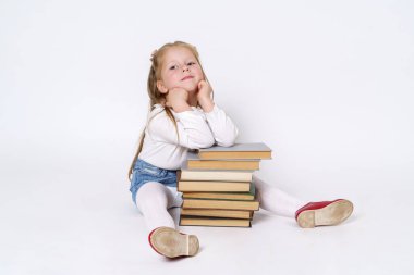 Eğitim ve insan kavramı. Kitapların yanında oturan ve onlara yaslanan genç bir kızın portresi. Beyaz arkaplan üzerinde izole edilmiş.