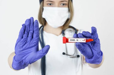 Tıp ve sağlık konsepti. Doktor elinde virüsün kan testlerini içeren bir test tüpü tutuyor. Öteki eliyle bir jest yapıyor. Dur..