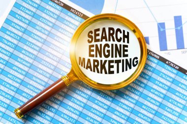 Finans ve iş konsepti. Mali raporlar, çizelgeler ve bir büyüteç masada. Büyüteçin içinde bir yazı var. Arama İşaretleme