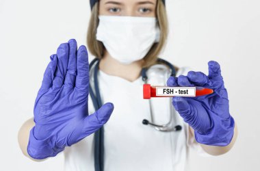 Tıp ve sağlık konsepti. Doktor elinde virüsün kan testlerinin yapıldığı bir tüp tutuyor. FSH, diğer eliyle bir jest yapıyor. Dur..