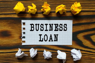 İş ve finans kavramı. Ahşap bir tahtanın üzerinde buruşmuş kağıt yaprakları ve üzerine yazdığı bir defterden bir yaprak var.