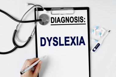 Tıp ve sağlık konsepti. Masanın üzerinde bir stetoskop, bir hap termometresi ve bir teşhis kağıdı var. Metin sayfaya DYSLEXIA tanısıyla yazılmıştır