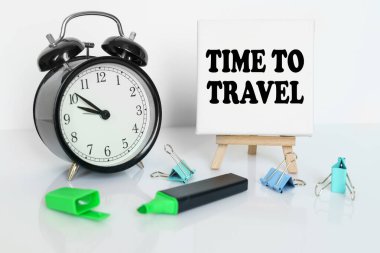 Zaman kavramı. Masanın üzerinde bir çalar saat, bir işaretleyici ve üzerinde yazılı bir tuval olan bir üçayak var.