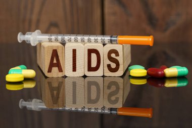 Tıp ve sağlık konsepti. Yüzeyde görünür tabletler, bir şırınga, ahşap ölür ve üzerine yazıldığı yansımaları - AIDS