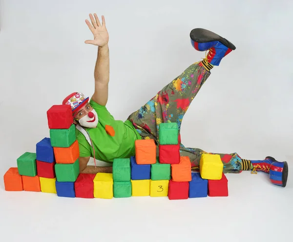 Святкова Весела Концепція Клоун Лежить Підлозі Різнокольоровими Кубиками Піднявши Руку — стокове фото