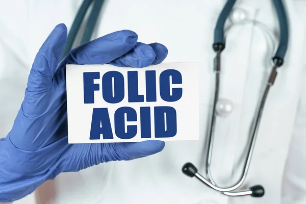 Medicine concept. The doctor holds a business card that says - FOLIC ACID