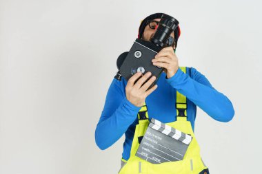 Kutlama ve iletişim konsepti. Parlak elbiseli bir palyaço film kamerasıyla çekim yapıyor. Beyazda izole edilmiş