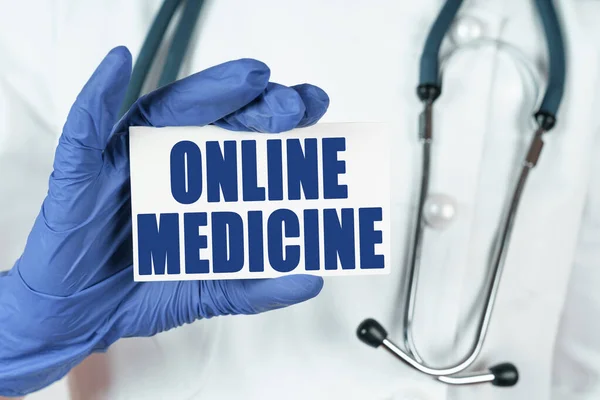 Medicine concept. The doctor holds a business card that says - ONLINE MEDICINE