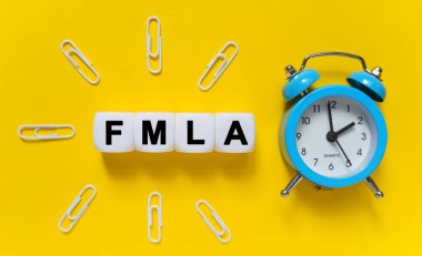 Finance and economics concept. On a yellow background, a blue alarm clock, paper clips and white cubes on which the text is written - FMLA clipart