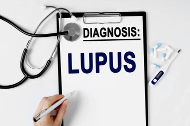 Tıp ve sağlık konsepti. Masanın üzerinde bir stetoskop, bir hap termometresi ve bir teşhis kağıdı var. Metin, LUPUS teşhisi ile birlikte kağıda yazılmıştır.