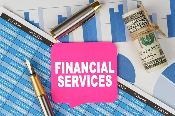 Business and finance concept. Among the financial statements and charts is a note with the text - FINANCIAL SERVICES