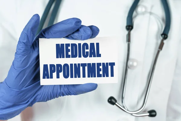 Medicine concept. The doctor holds a business card that says - MEDICAL APPOINTMENT