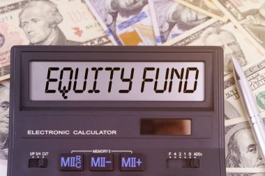 İş ve finans kavramı. Masanın üzerinde dolar ve elektronik panoda EQUITY FUND yazan bir hesap makinesi var.