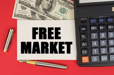 İş ve finans kavramı. Kırmızı bir arkaplanda, paranın yanında, bir hesap makinesi ve bir kalem - FREE MARKET - metinde bir işaret yatar