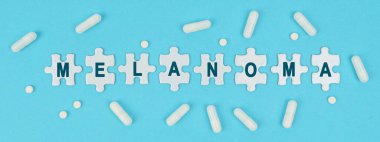 İlaç ve sağlık. Mavi arka planda, haplar ve yazıtlarda bulmacalar var, Melanom.