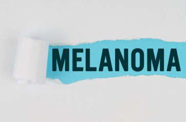 Tıp ve sağlık konsepti. Beyaz bir kağıt parçasının ortasında, altında mavi bir arkaplan olan bir gözyaşı yapılır. Yazıt - Melanom