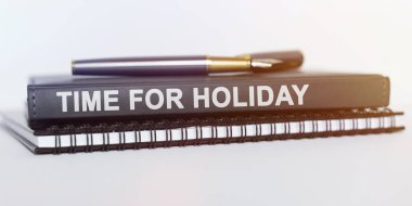 İş ve eğitim kavramı. Masanın üzerinde bir defter, bir kalem ve bir kitap var. Kitap diyor ki - Tatil zamanı