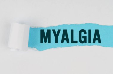 Tıp ve sağlık konsepti. Beyaz bir kağıt parçasının ortasında, altında mavi bir arkaplan olan MYALGIA yazısını içeren bir gözyaşı yapılır.