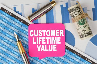 Business and finance concept. Among the financial statements and charts is a note with the text - CUSTOMER LIFETIME VALUE