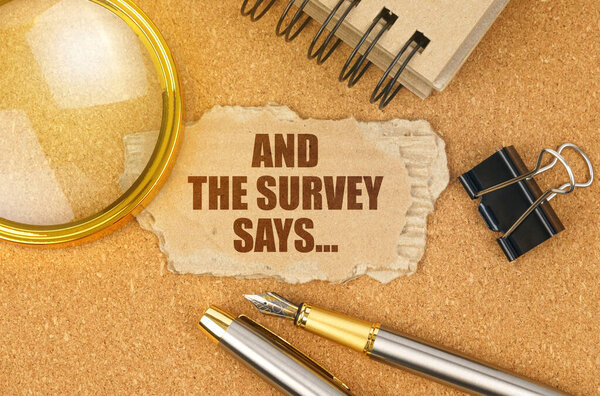 Концепция бизнеса и финансов. На столе - канцелярские принадлежности и картон с надписью - И СУРВИ ГОВОРИТ