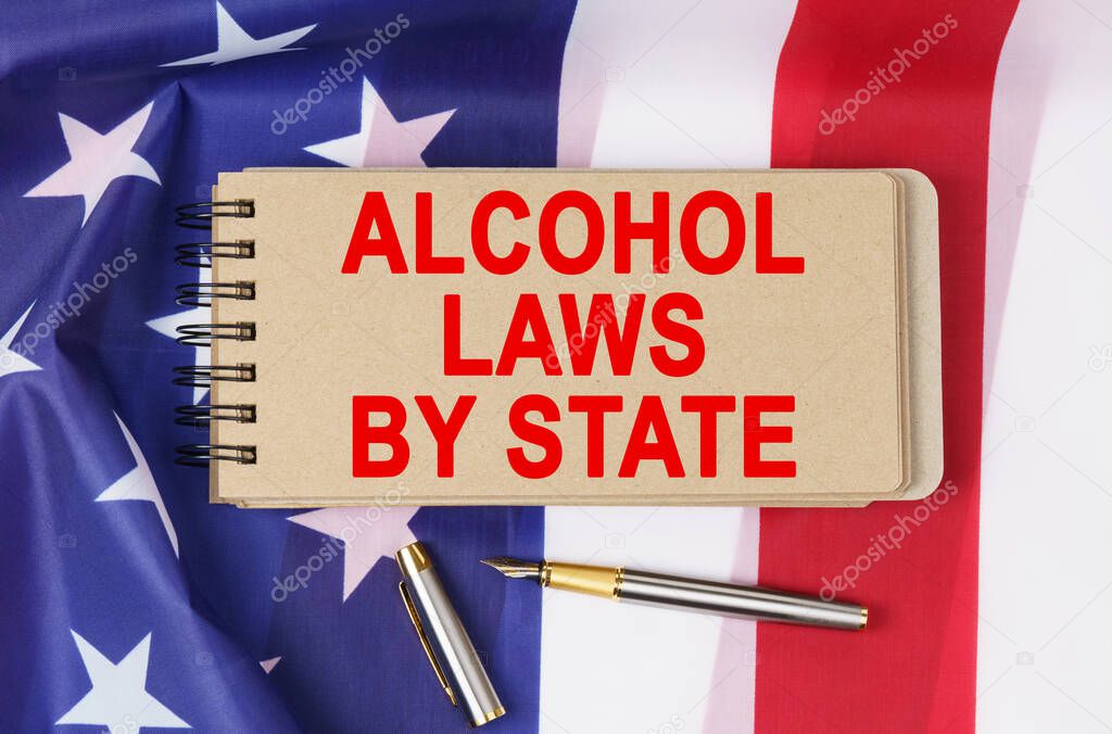 Law and order concept. Against the background of the flag of the United States of America lies a notebook with the inscription - ALCOHOL LAWS BY STATE