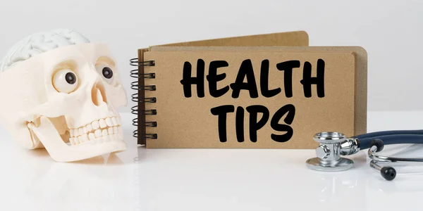 Medicine and health concept. On the table lies a skull, a stethoscope and a notebook with the inscription - HEALTH TIPS