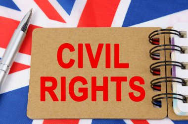 Hukuk ve adalet kavramı. Büyük Britanya bayrağının arka planında üzerinde CIVIL hakları yazan bir defter yatıyor.