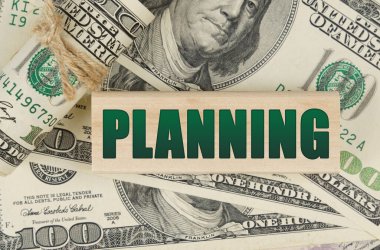 İş ve finans kavramı. Dolarların üzerinde, üzerinde yazı olan ahşap bir levha var.