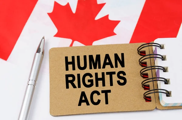 Law and justice concept. Against the background of the flag of Canada lies a notebook with the inscription - HUMAN RIGHTS ACT