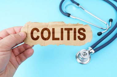 Tıp ve sağlık konsepti. Mavi arka planda, adamın biri üzerinde COLITIS yazan bir karton kutu tutuyor.