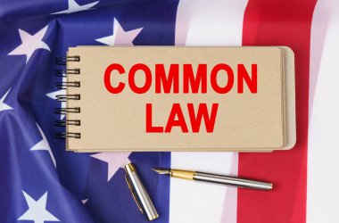 Kanun ve düzen kavramı. Amerika Birleşik Devletleri bayrağının arka planında üzerinde COMMON Kanunu yazan bir defter yatıyor.