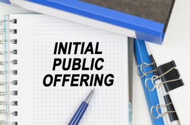 İş ve Ekonomi. Belgeler arasında, klasörler arasında, üzerinde yazı olan bir defter - INITIAL PUBLIC Önerme