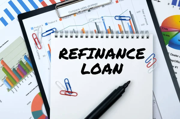 Business and finance. On the table are reports, charts, a notebook with the inscription - REFINANCE LOAN