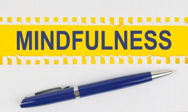 İş ve finans. Masanın üzerinde bir defterden iki sayfa ve sarı arkaplanda bir kalem var - MINDFULNESS