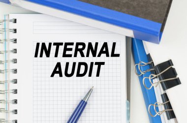 İş ve Ekonomi. Belgeler arasında, klasörler, üzerinde yazı olan bir defter - InterTERNAL AUDIT