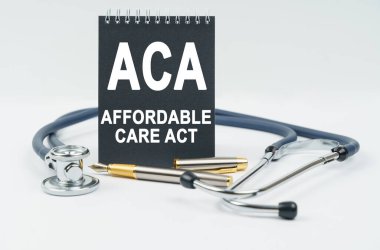 Tıp ve sağlık konsepti. Beyaz arka planda steteskop, kalem ve siyah defter bulunur.