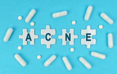 İlaç ve sağlık. Mavi arka planda, üzerinde ACNE yazan haplar ve bulmacalar var.